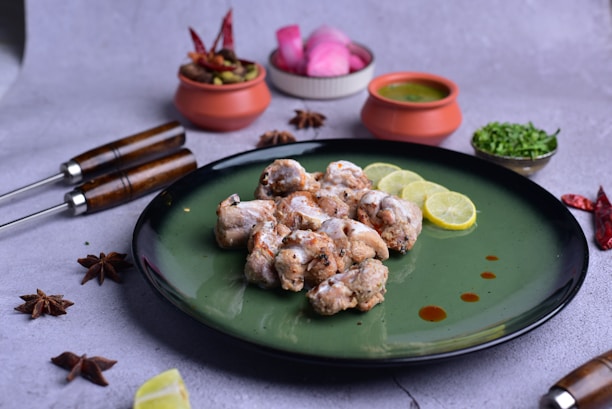 A sizzling platter of spicy grilled chicken garnished with fresh herbs and lemon wedges.