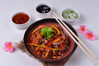 A beautifully plated Asian fusion dish featuring grilled meats, vibrant vegetables, and colorful garnishes in a warm, inviting dining setting.