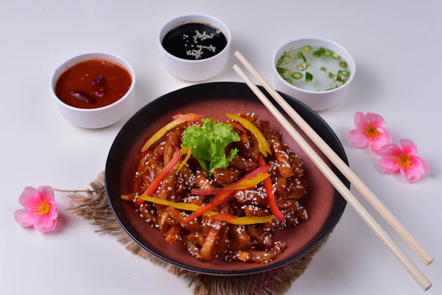 A beautifully plated Asian fusion dish featuring grilled meats, vibrant vegetables, and colorful garnishes in a warm, inviting dining setting.