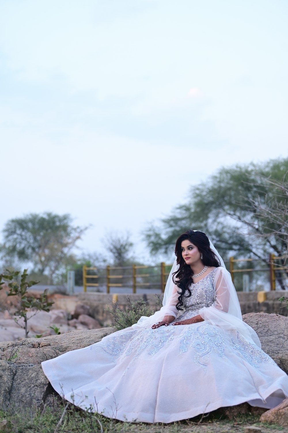 a woman in a wedding dress sitting on a rock