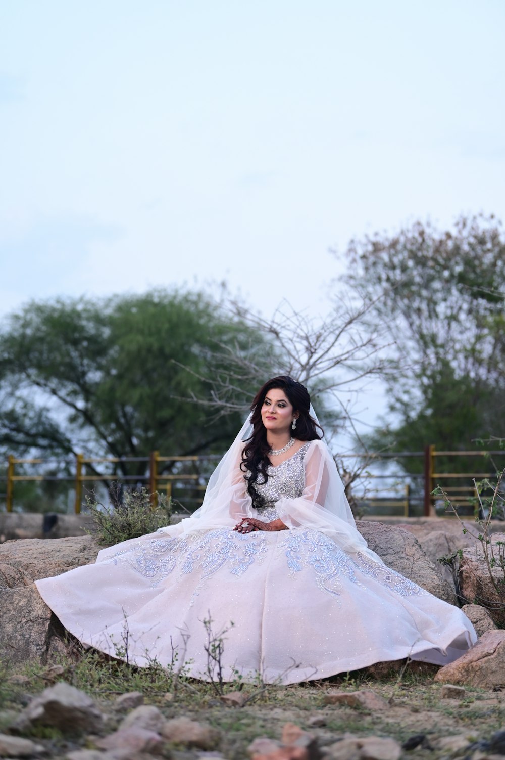 a woman in a wedding dress sitting on rocks