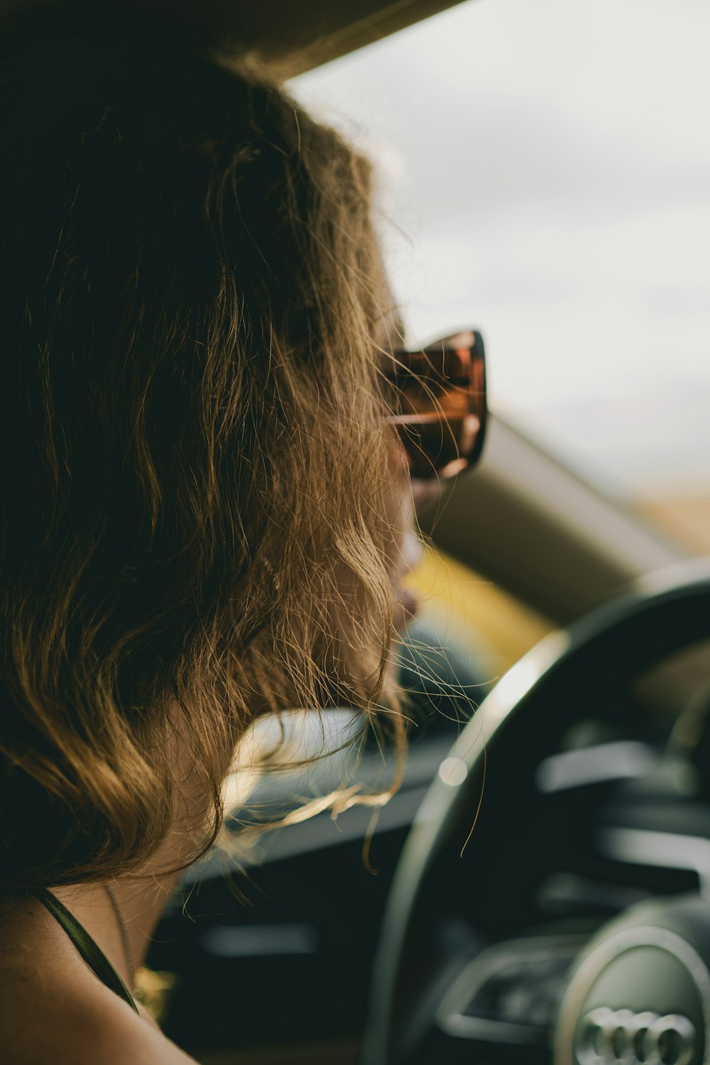 a woman driving a car with a steering wheel