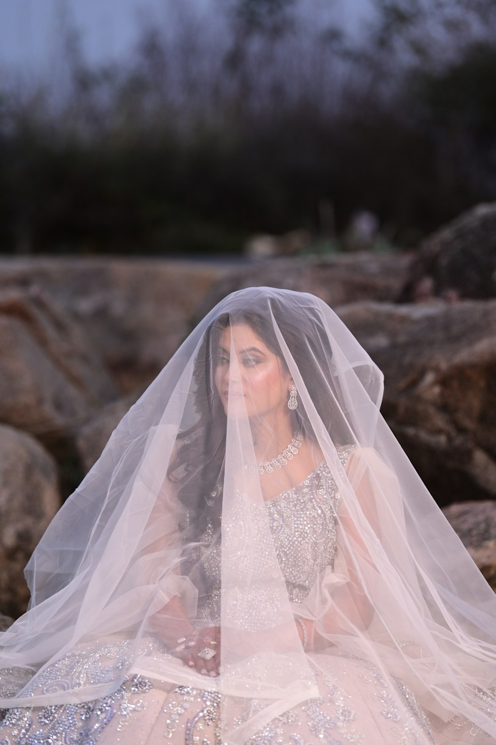 a woman in a wedding dress sitting on rocks
