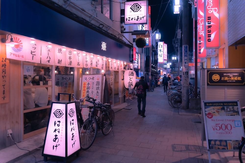 a city street at night with signs and bicycles