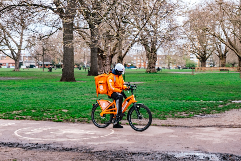 a person in an orange jacket is riding a bike