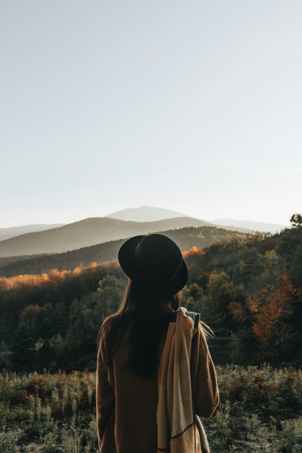 uma mulher em pé em um campo com montanhas no fundo