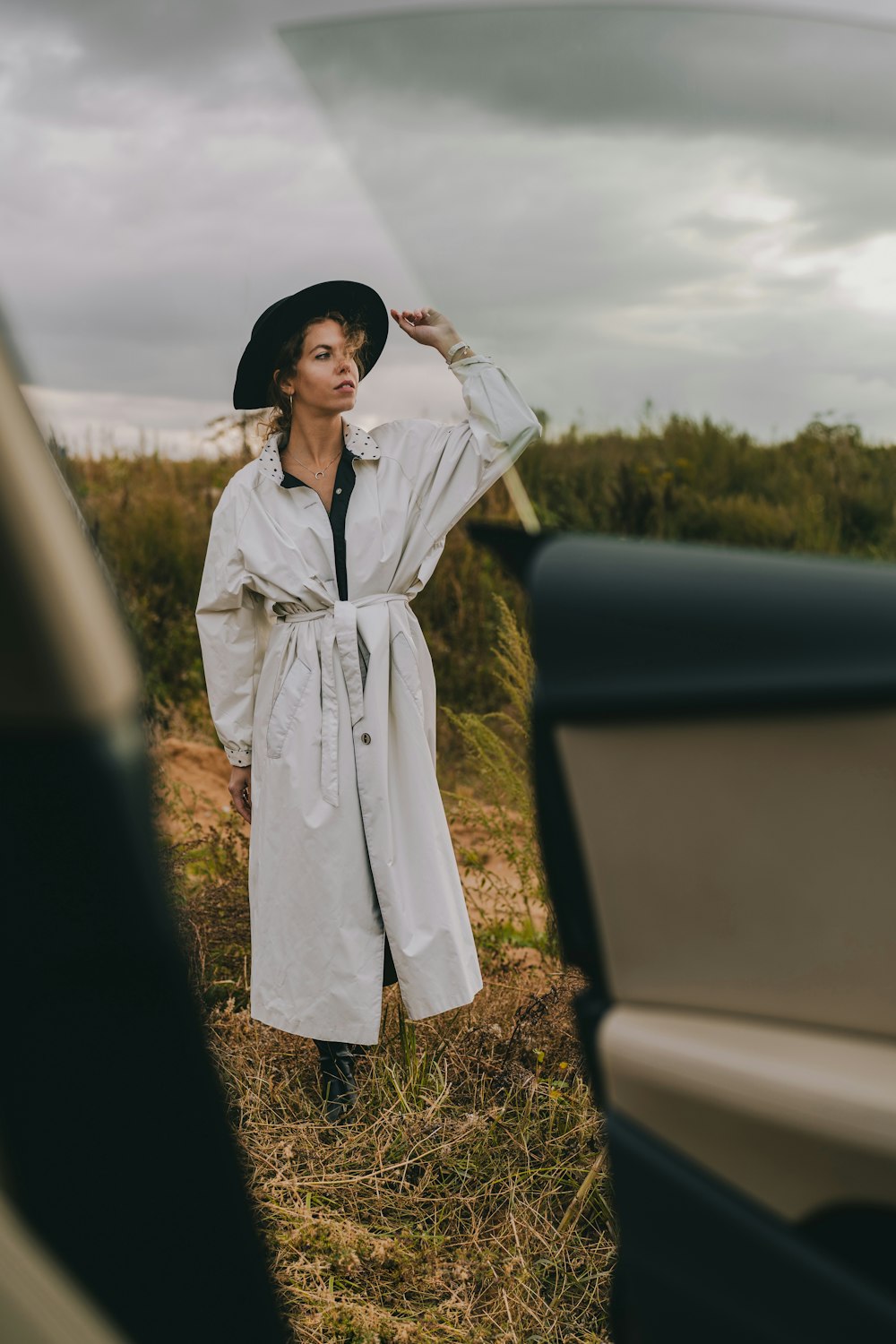 a woman in a white coat and hat standing next to a car