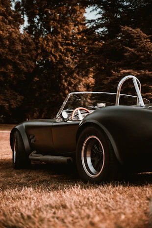 A gleaming restored vintage convertible parked on a sunlit Mallorca coastal road at golden hour.