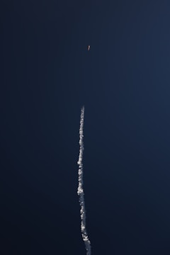 Young students launching a water rocket outdoors with excitement under a clear sky.