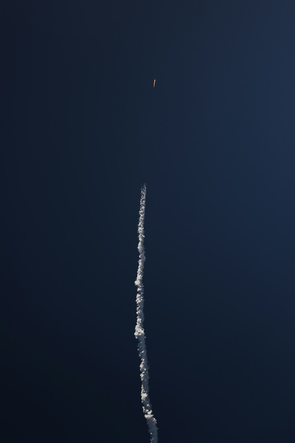 a plane flying in the sky leaving a trail of smoke