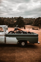 Close-up of a high-cylinder motorcycle being loaded onto a stylish turquoise flatbed truck.