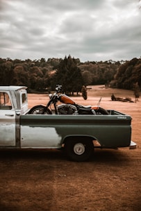 Close-up of a high-cylinder motorcycle being loaded onto a stylish turquoise flatbed truck.