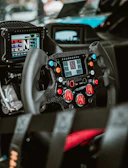 Top view of a racing steering wheel with illuminated green buttons.