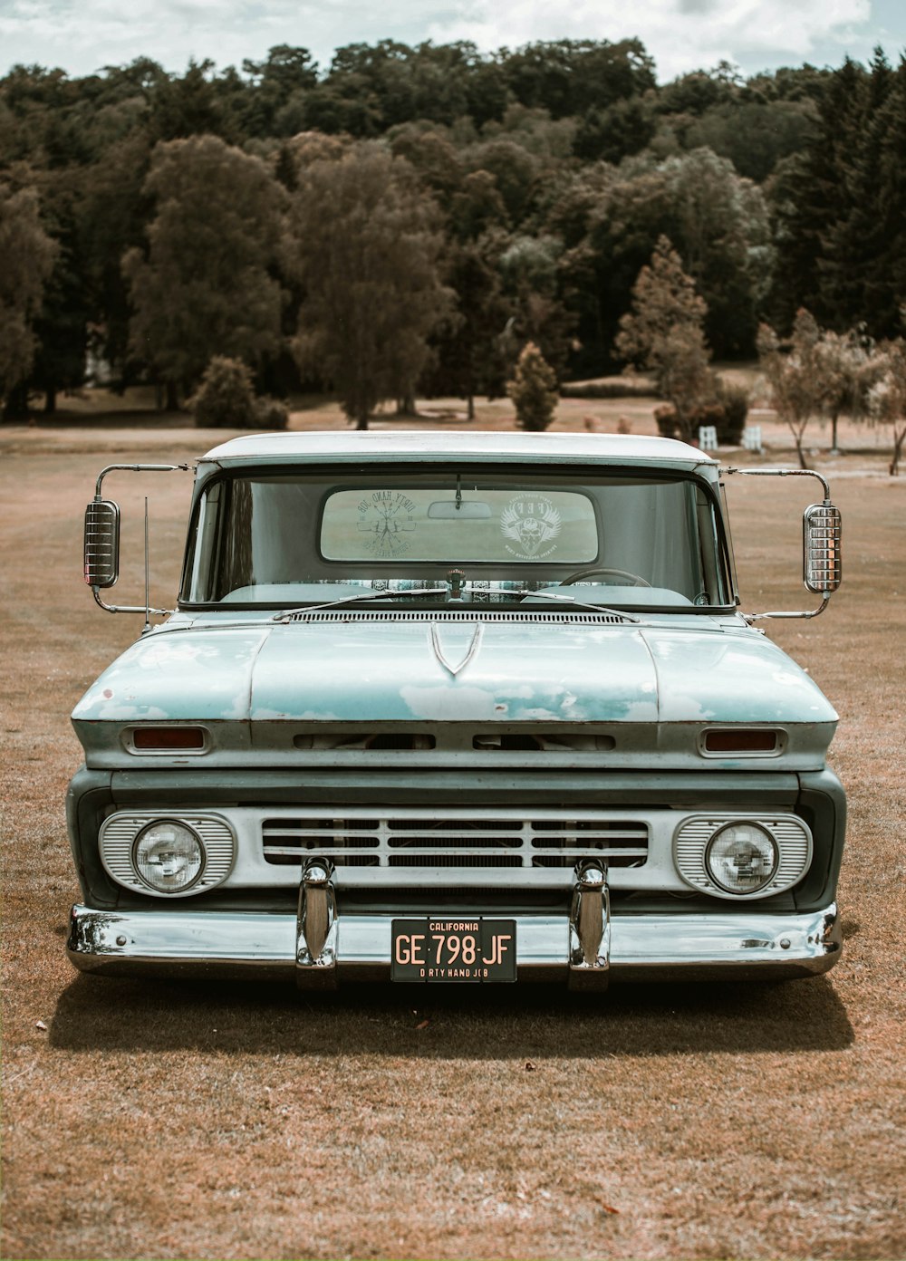 an old truck parked in a field with trees in the background