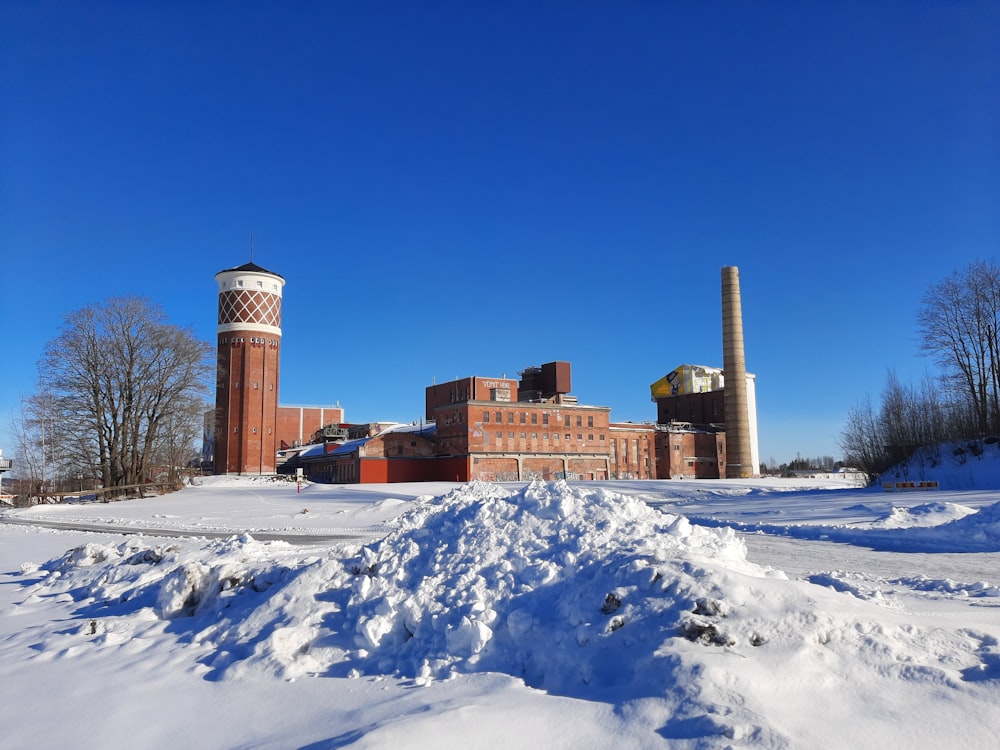 a snow covered field with a factory in the background