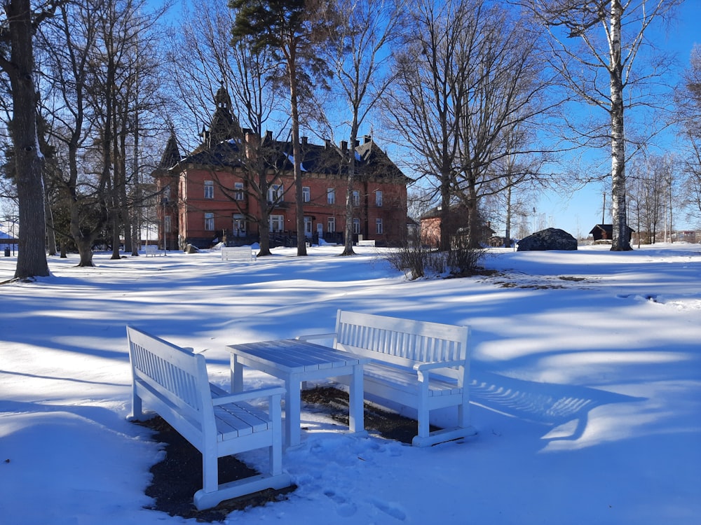 a couple of white benches sitting in the snow