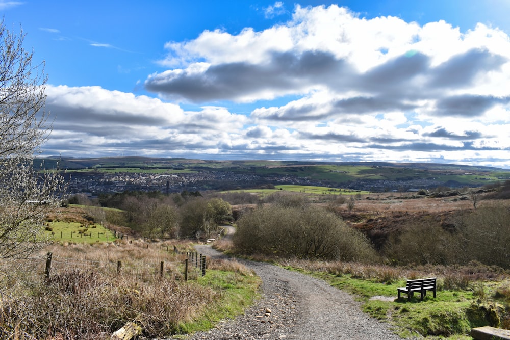 a dirt road with a bench on the side of it