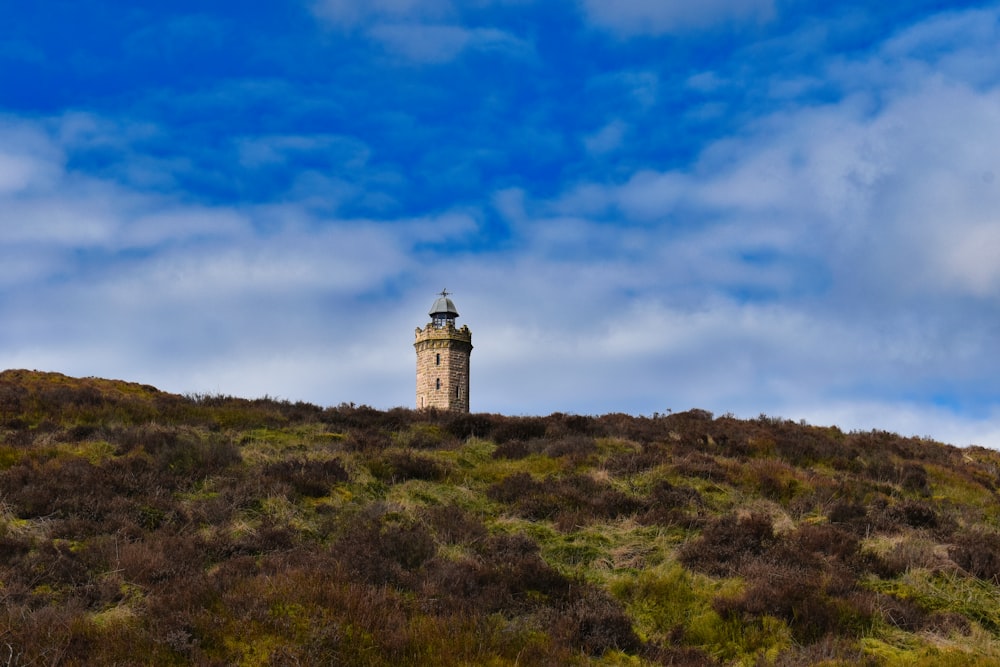 a tall tower on top of a grassy hill