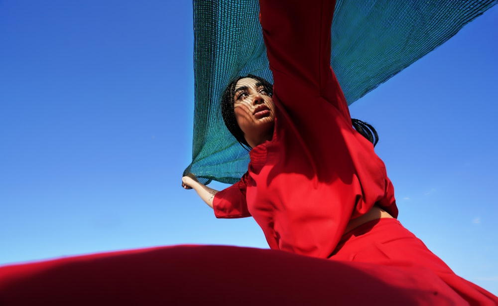 a woman in a red dress is holding a green umbrella