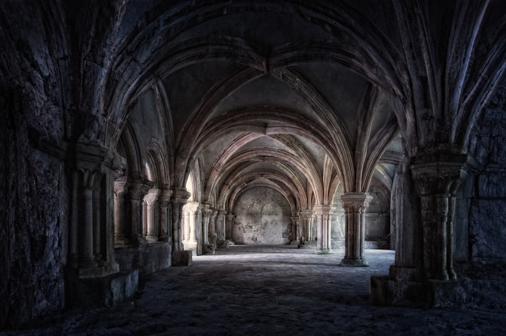 a dark room with arches and a stone floor