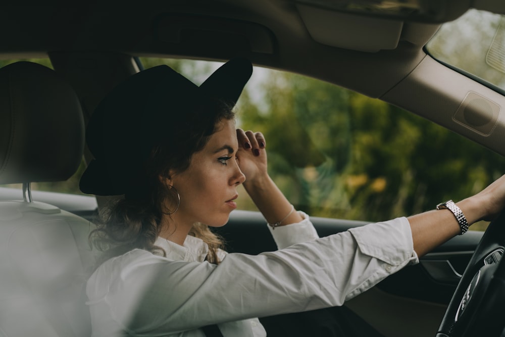 a woman sitting in a car with her hand on the steering wheel