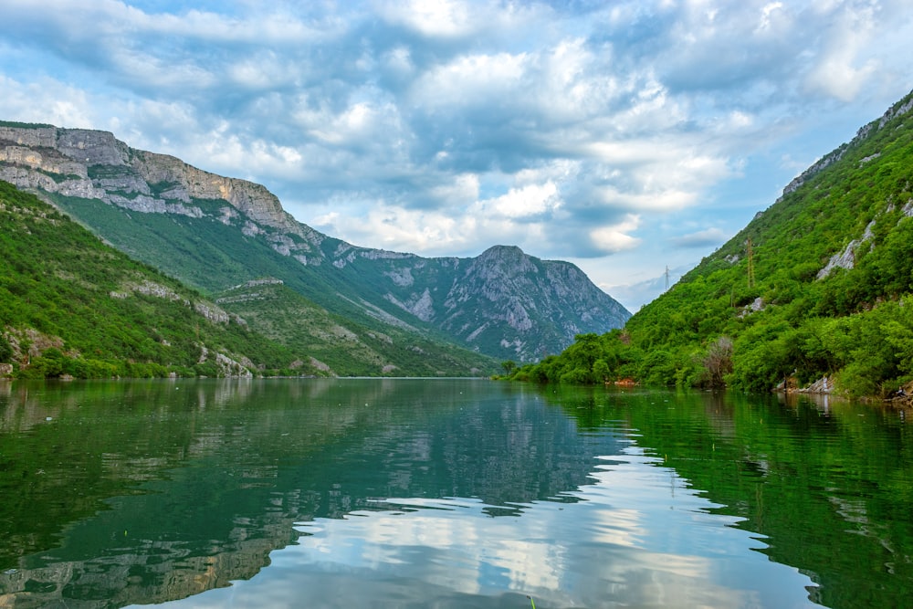 a body of water surrounded by mountains under a cloudy sky