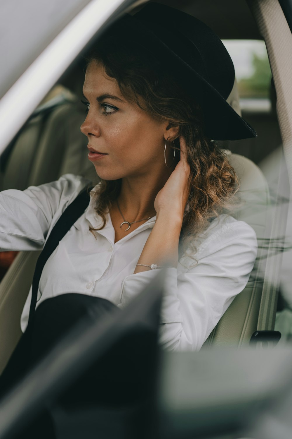 a woman sitting in a car wearing a hat