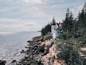 Exterior view of The Crooked Lighthouse vacation home nestled among tall pines under a bright blue sky.