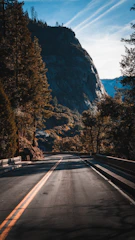 A serene mountain road winding through misty hills under a clear sky.