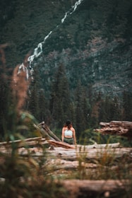 a woman standing on a log in the woods
