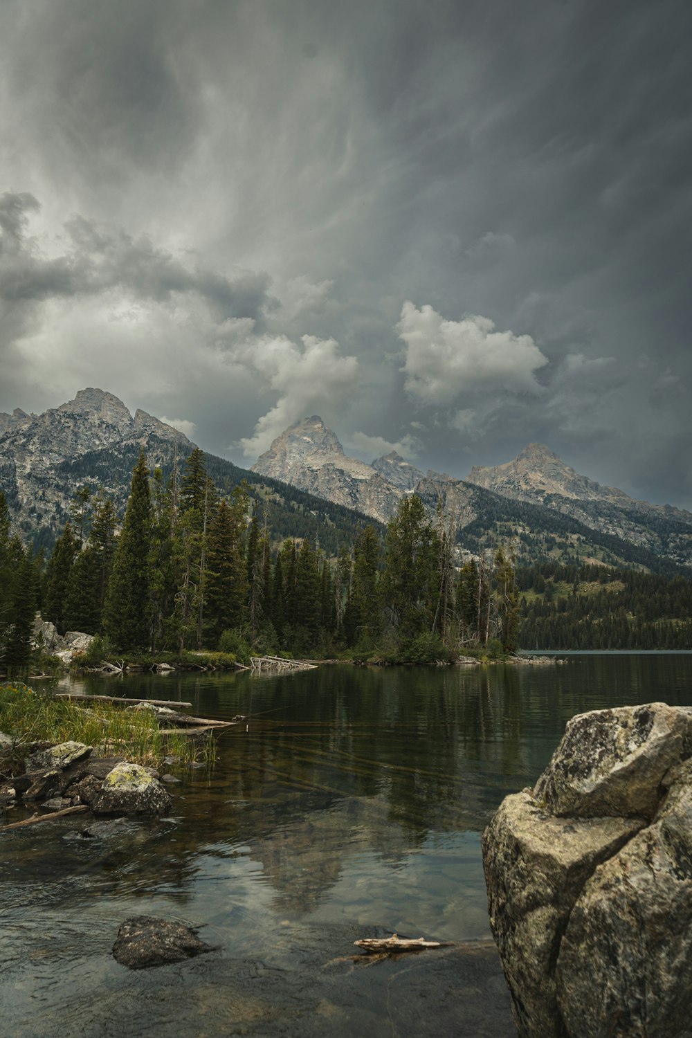 a body of water surrounded by mountains under a cloudy sky