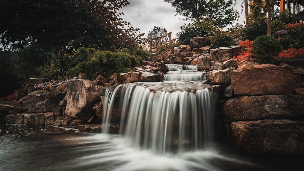 a waterfall is flowing over rocks into a pond