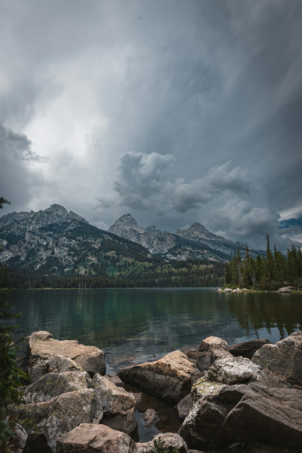 a lake surrounded by large rocks under a cloudy sky