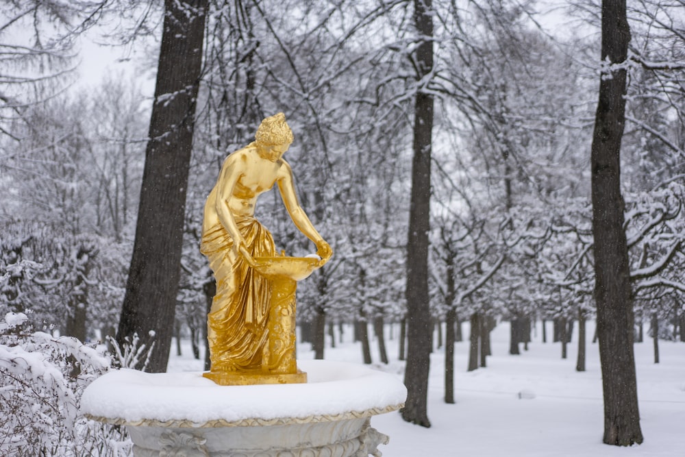 a golden statue sitting on top of a snow covered ground