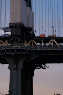 Close-up of a technician inspecting an infrastructure on a bridge with safety gear.