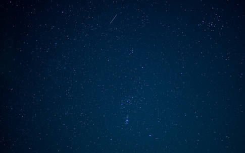 A serene image of a cosmic night sky with glowing stars and zodiac symbols softly illuminated.