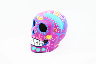 Artisan crafting a detailed paper mache skull with vibrant paints and fine brushwork.