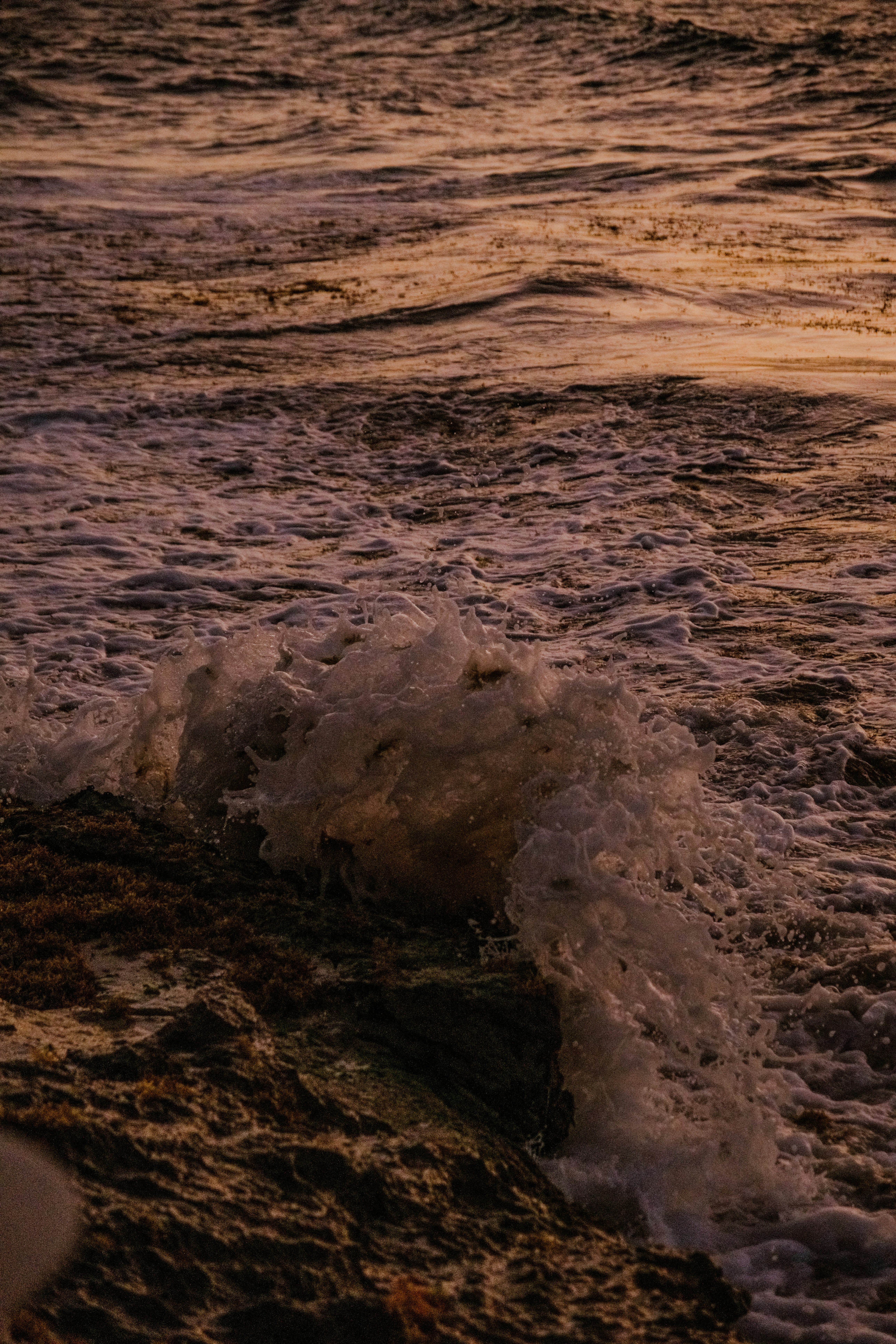 a surfboard sitting on top of a wave covered beach