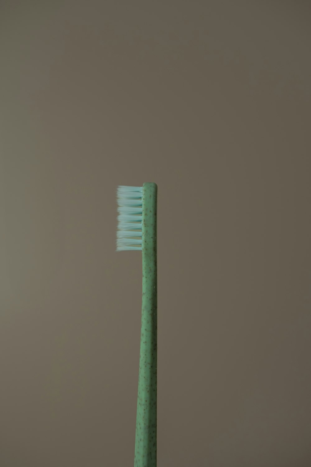 uno spazzolino da denti verde seduto sopra un tavolo