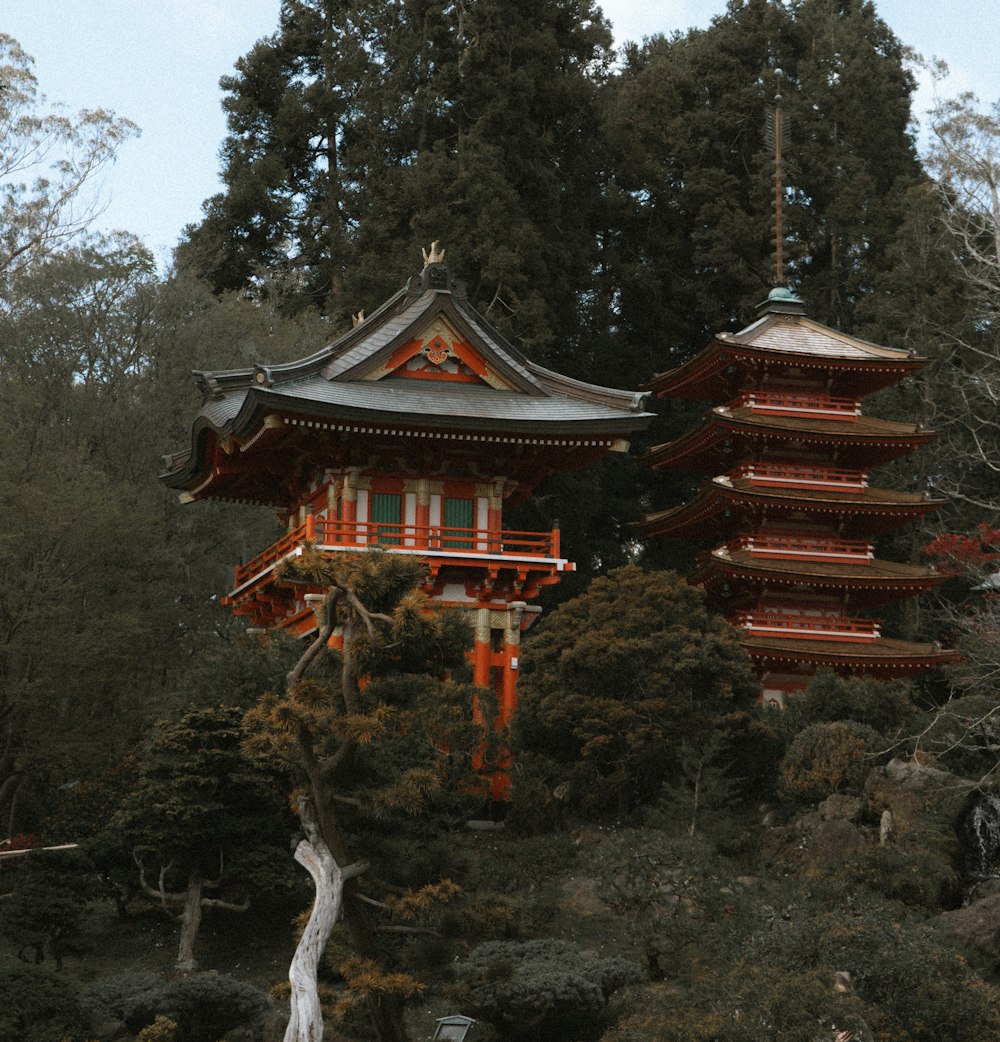 a tall red pagoda sitting on top of a lush green hillside