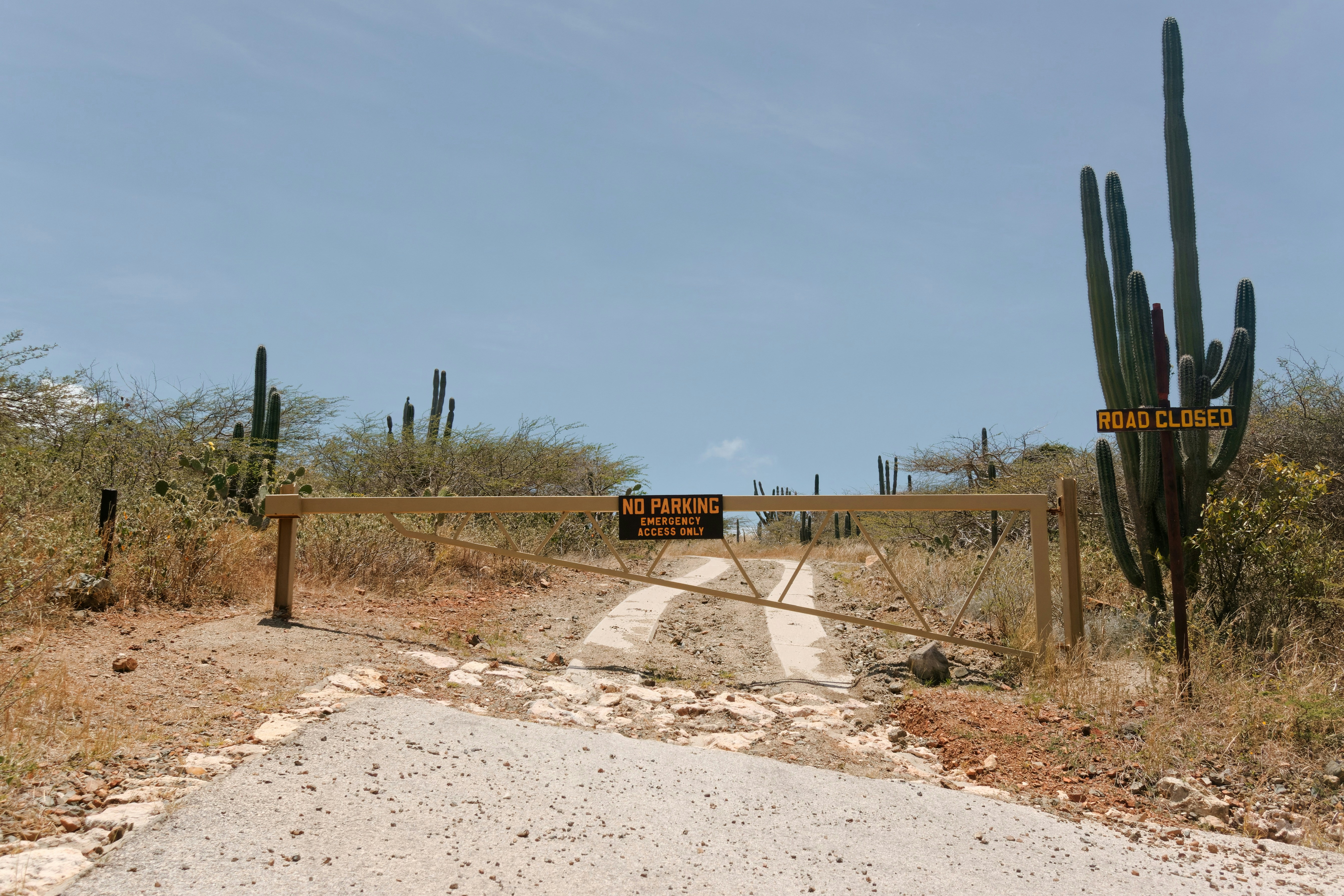 a dirt road with a gate and a sign on it