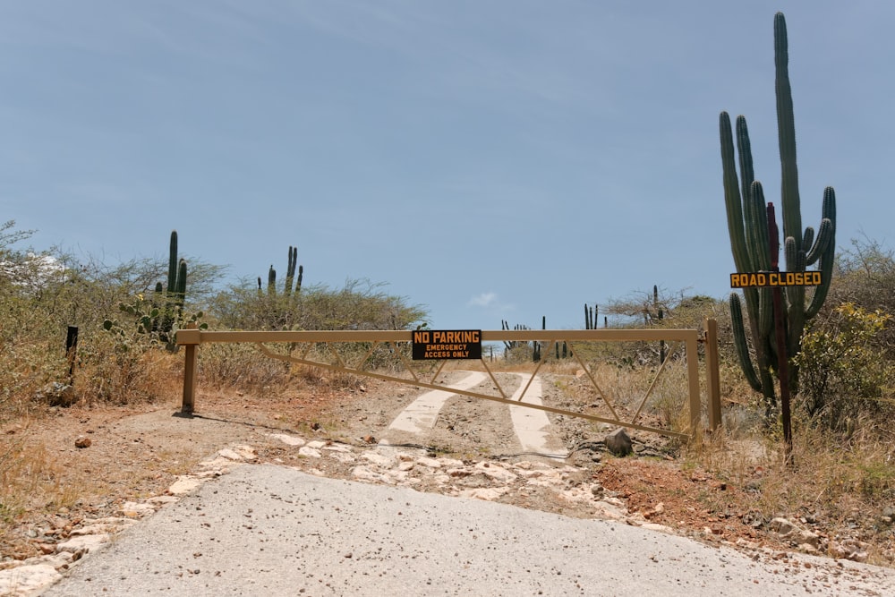 a dirt road with a gate and a sign on it