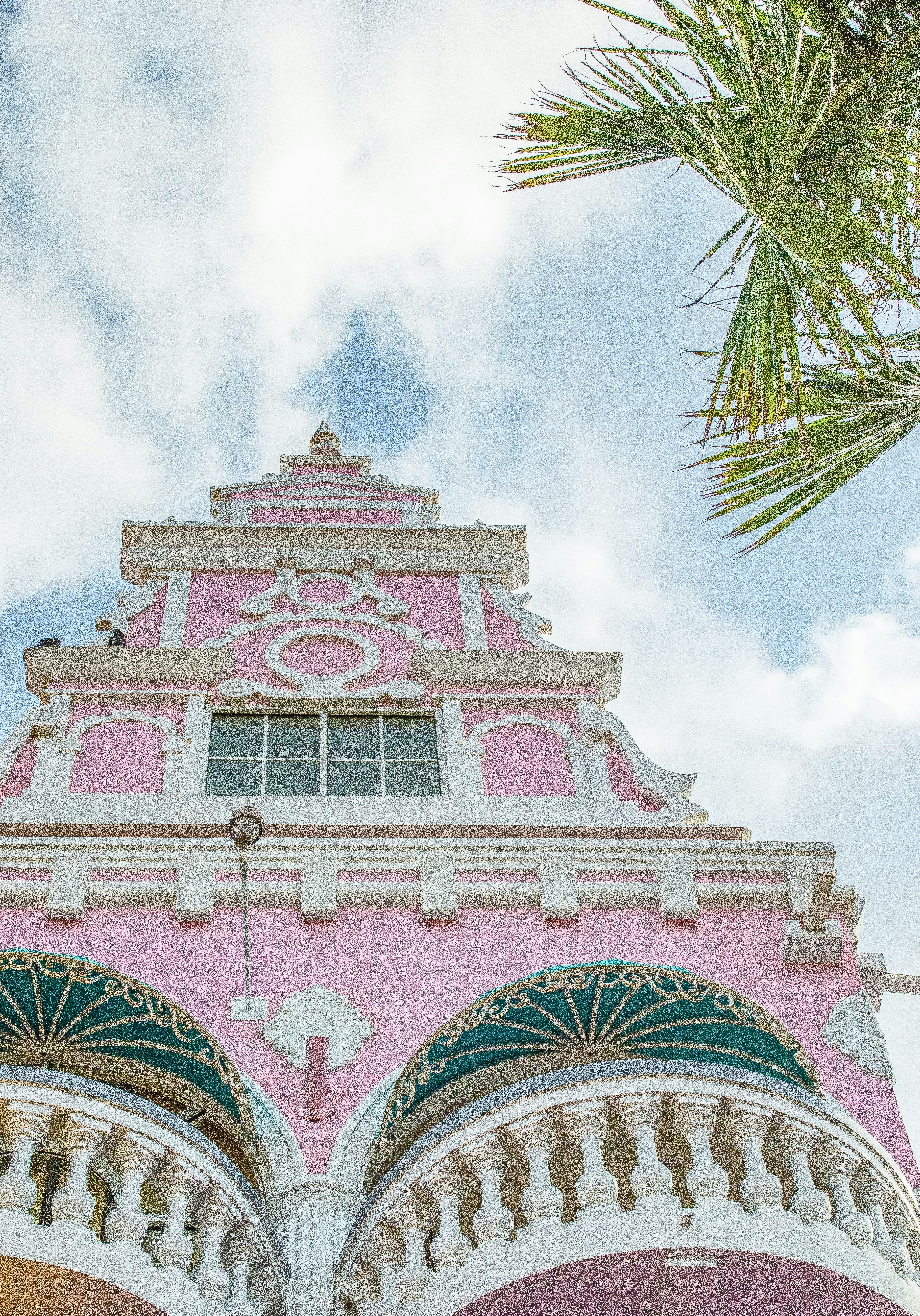 a pink and white building with a palm tree in the background