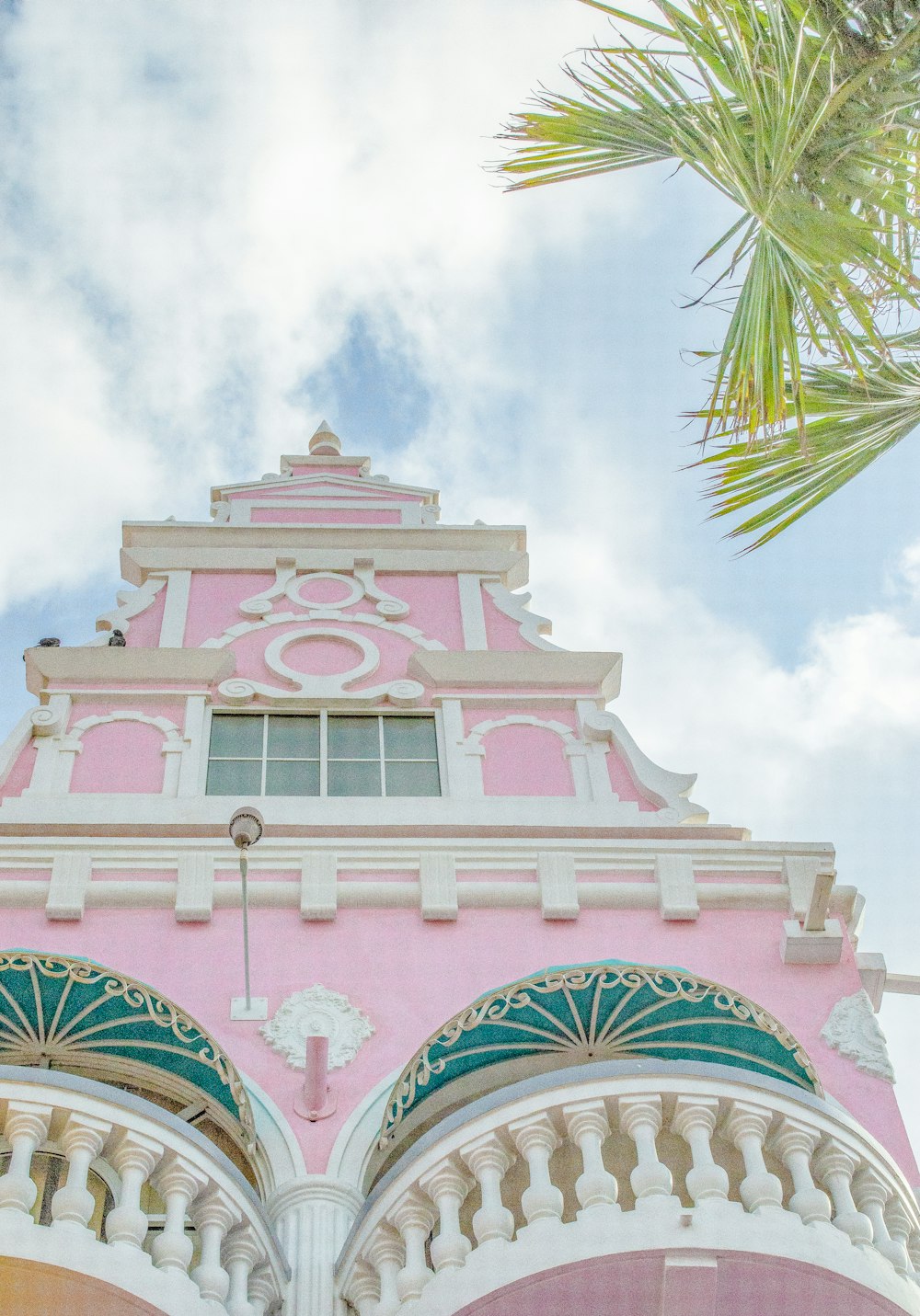 Un edificio rosa e bianco con una palma sullo sfondo