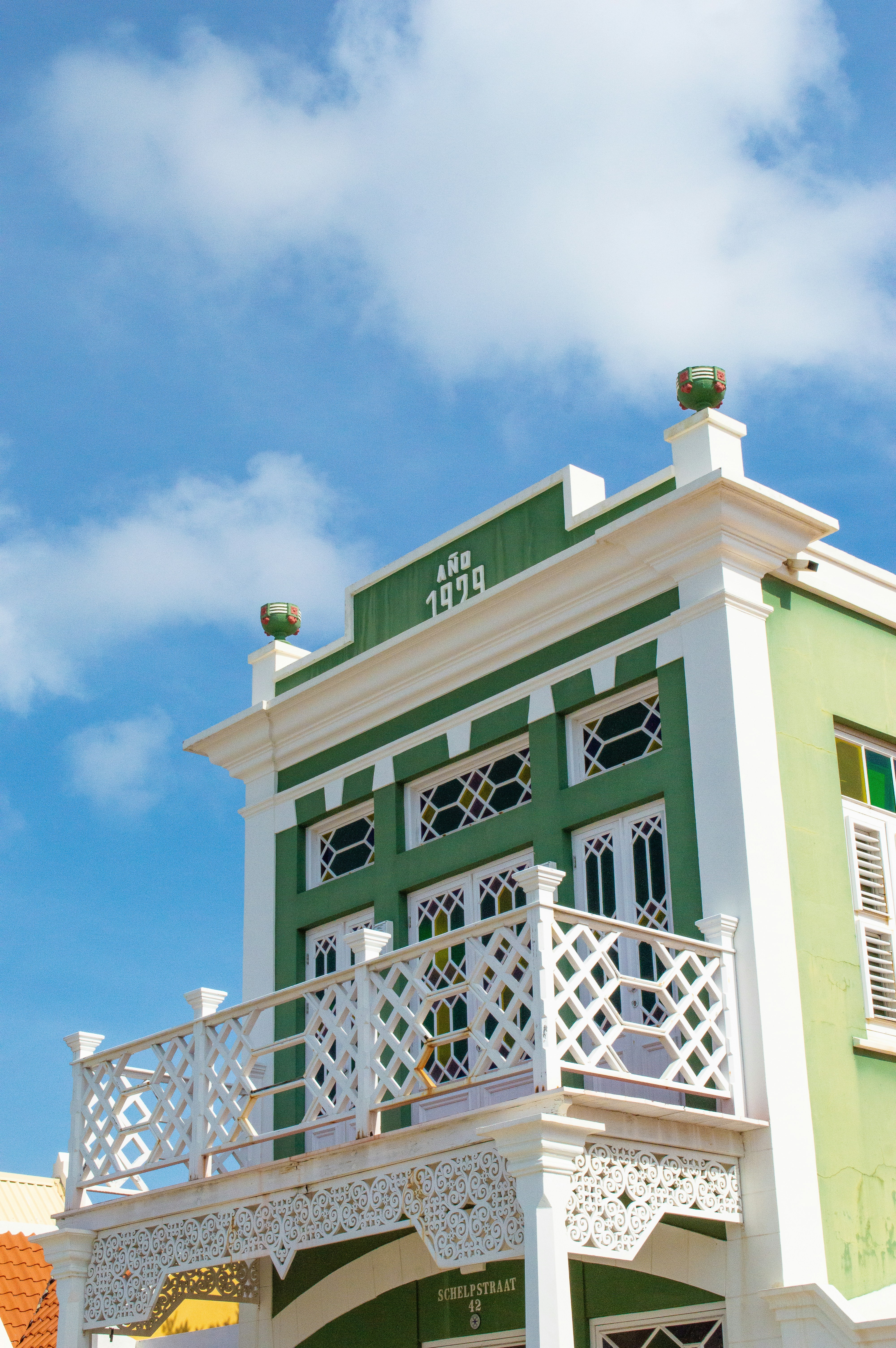 a green and white building with a balcony