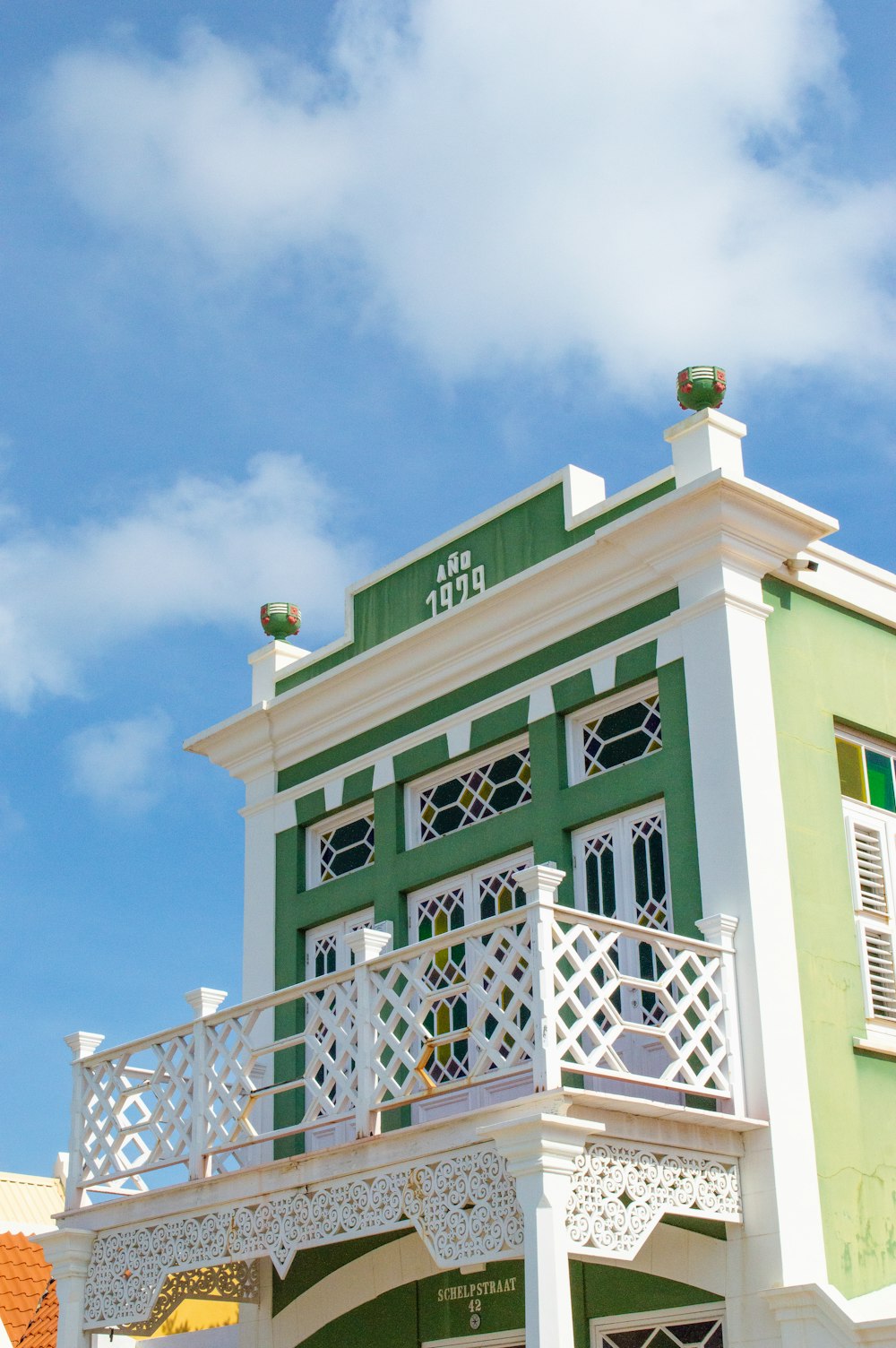 a green and white building with a balcony