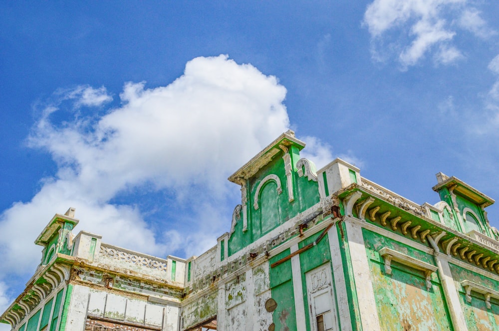 a green and white building with a sky background