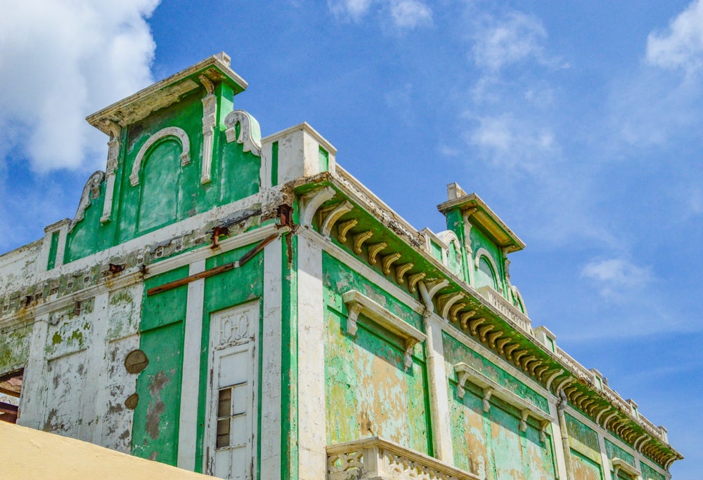 a green and white building with a sky background