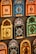 Colorful decorative items resembling miniature window frames are displayed. Each piece is intricately designed with various patterns, featuring bold colors like orange, blue, yellow, and green. Some have small wooden doors with detailed carvings and floral motifs.