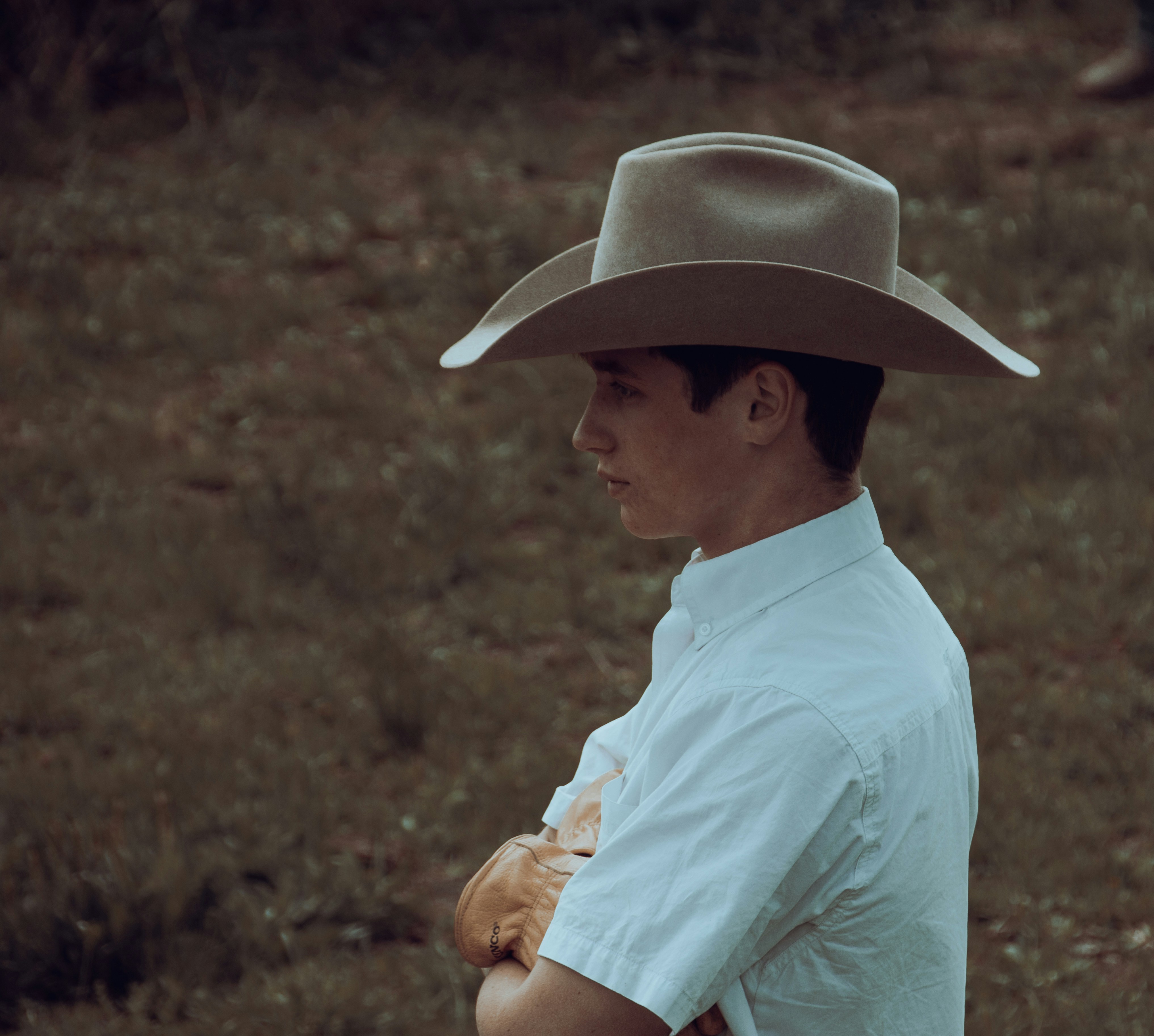 A man in a cowboy hat standing in a field photo – Free Man Image on ...